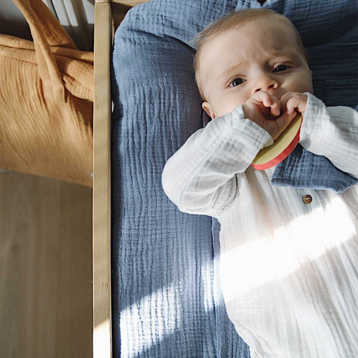 Bébé allongé sur un matelas à langer avec ousse bleu jean