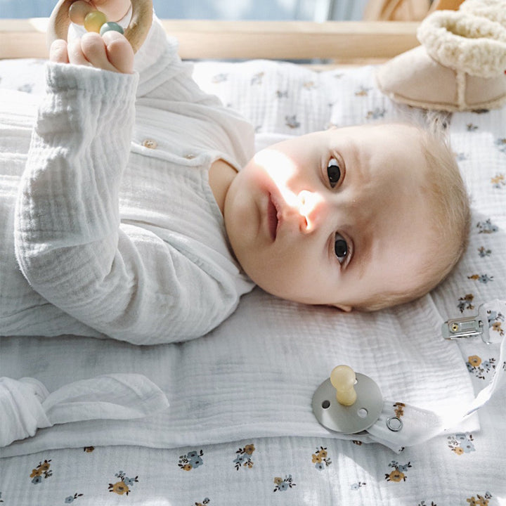 Bébé allongé sur un matelas à langer avec une housse fleurs