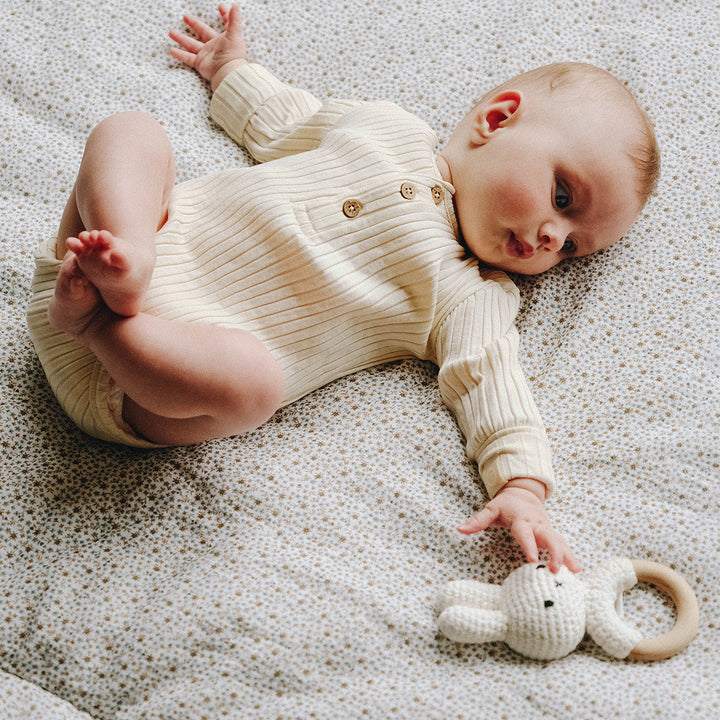 Bébé allongé sur une couette fleurs fougere