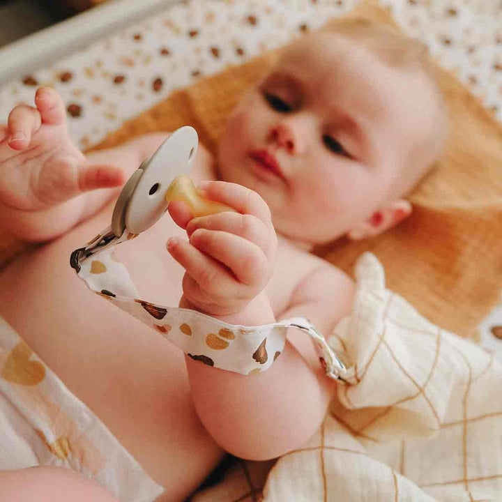 Bébé avec son attache tétine léopard