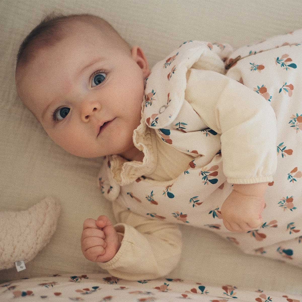 Baby wearing a GOTS organic cotton sleeping bag with pear motif