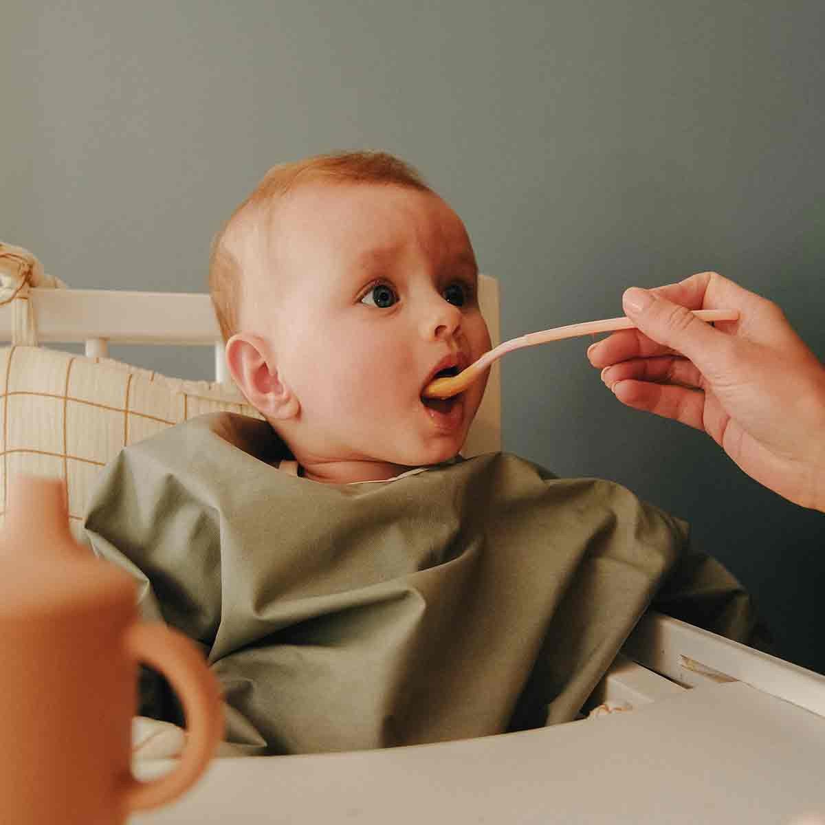 Baby with sage green long-sleeved bib