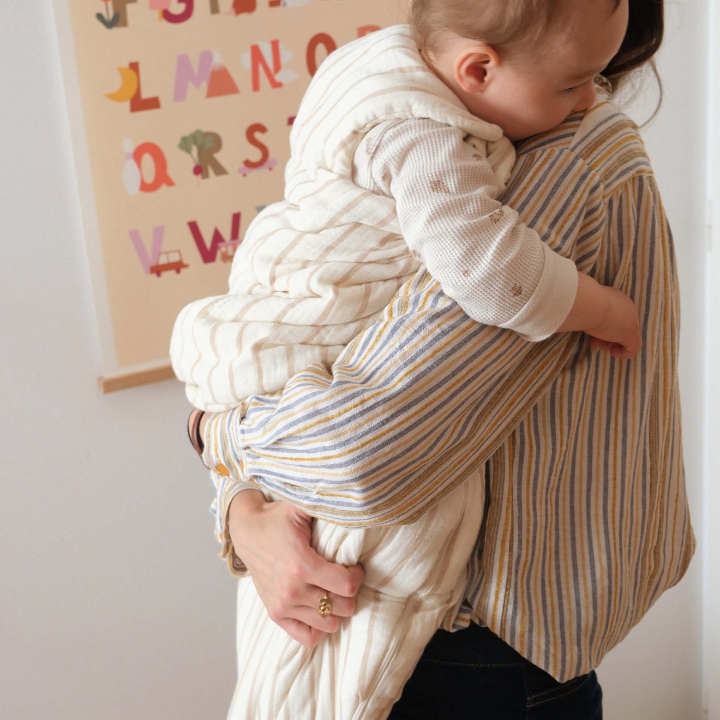 Bébé et sa maman avec une gigoteuse hiver à rayures beige