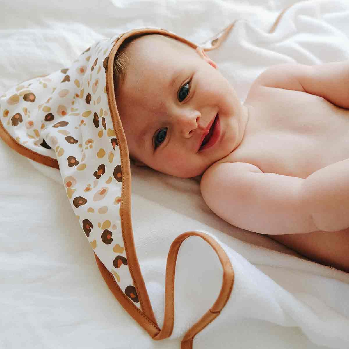 Bébé souriant allongé dans une cape de bain léopard