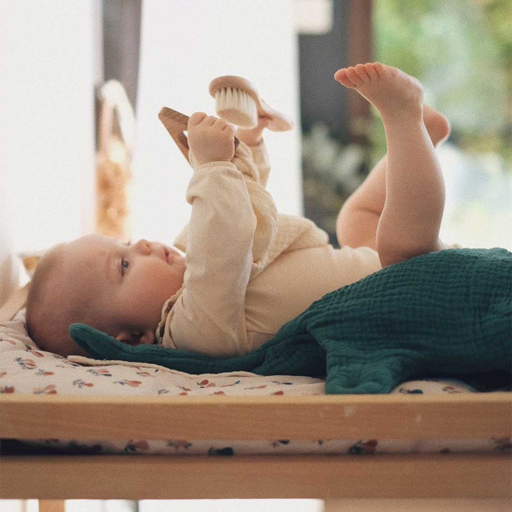 Bébé sur matelas à langer avec une housse poires