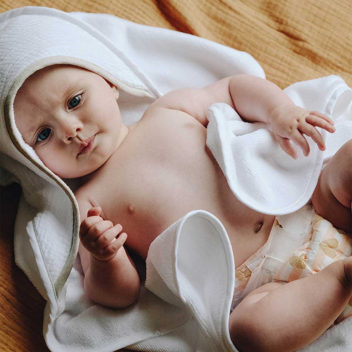 Bébé enveloppé dans une cape de bain blanche à biais lin