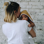 Baby in his mother's arms with a camel bath cape