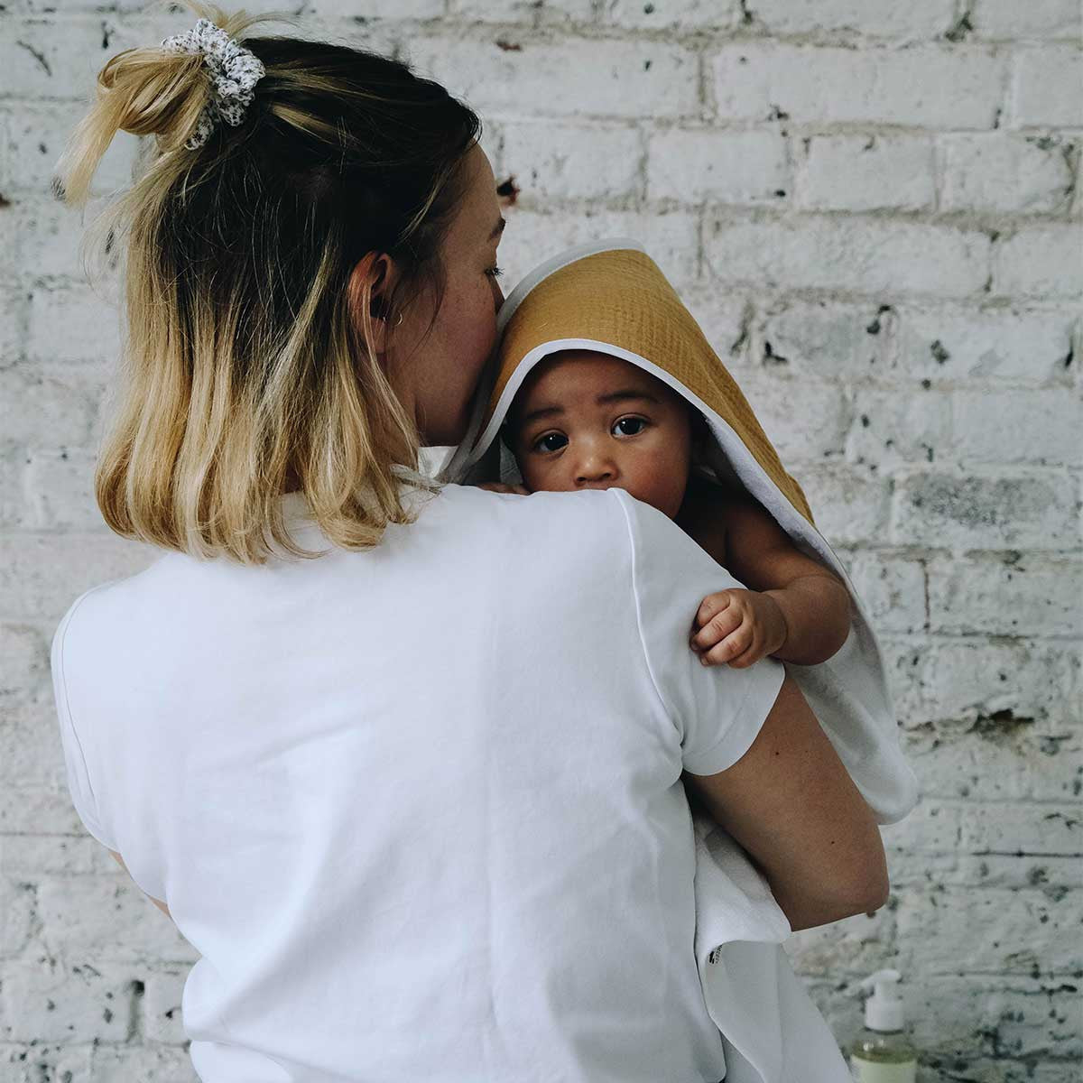 Baby in his mother's arms with a camel bath cape