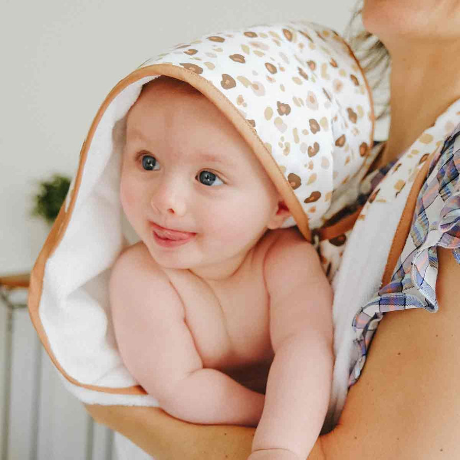 Bébé enveloppé dans un tablier de bain à motif léopard en éponge de bambou