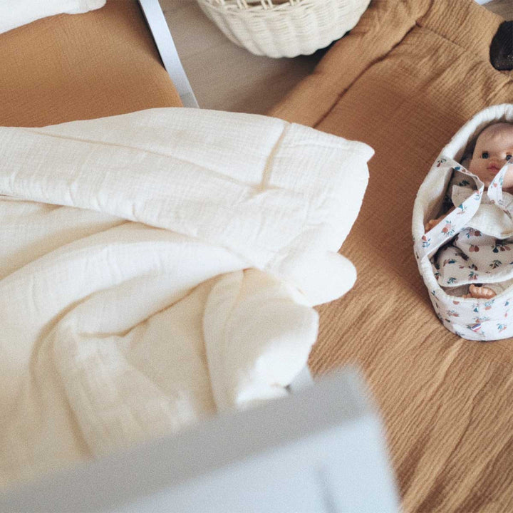 couette bébé en gaze de coton ecru dans un lit enfant