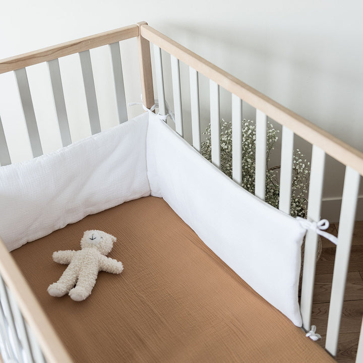 Drap housse en gaze de coton camel dans lit de bébé