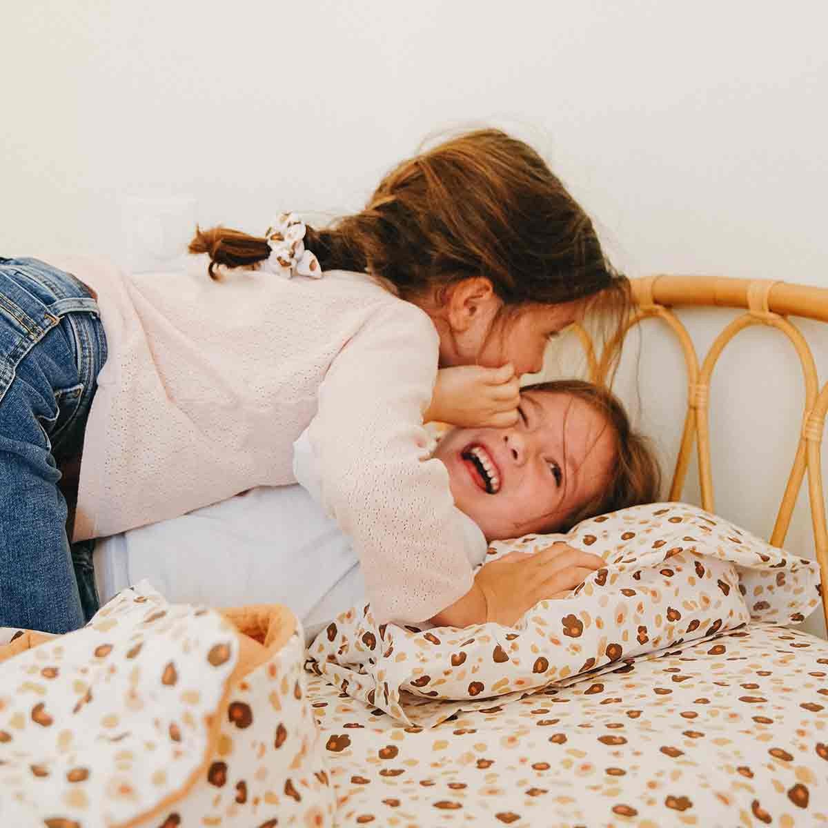 Two children on a leopard fitted sheet