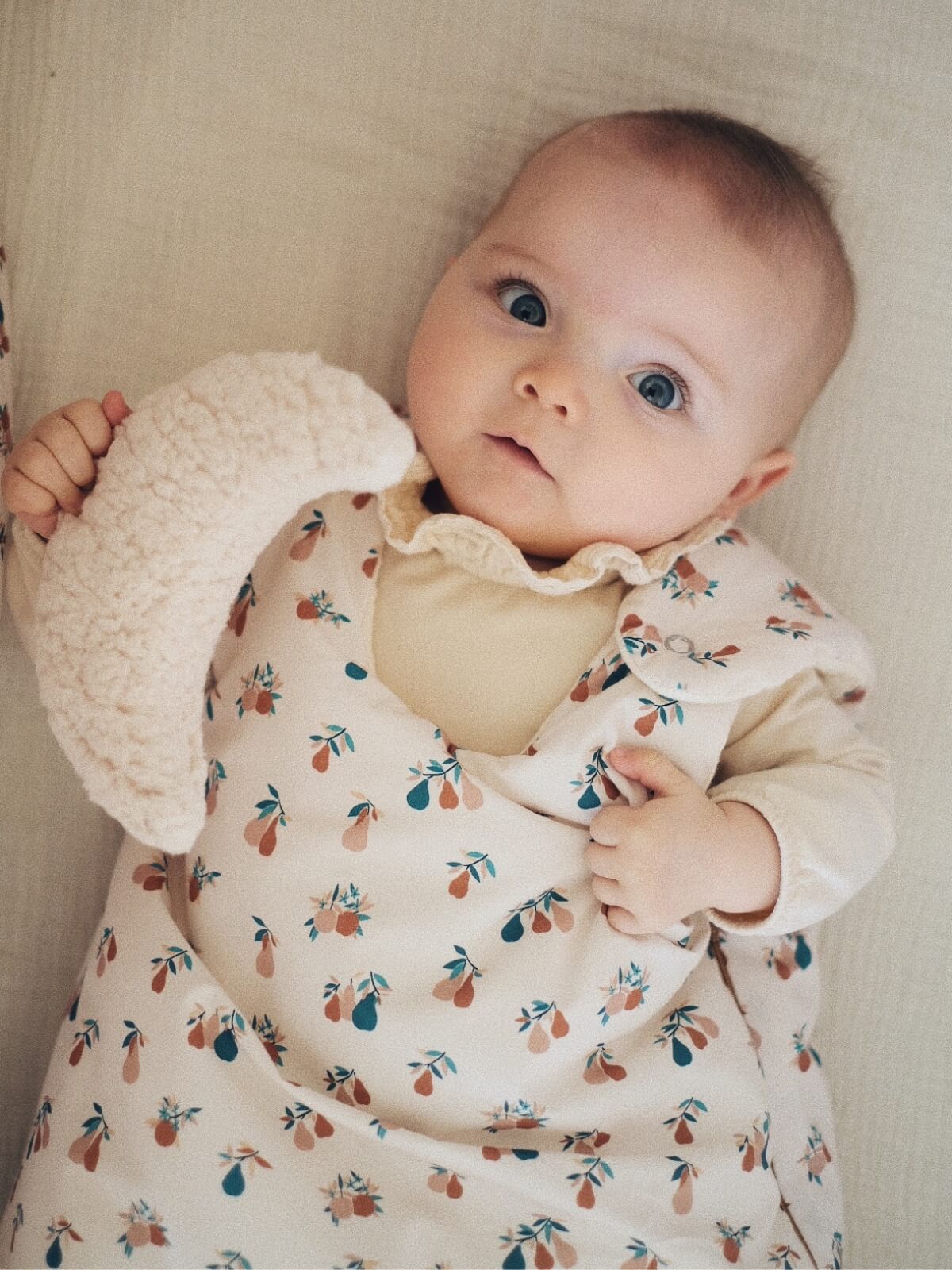 Baby in an organic cotton sleeping bag with a pear motif