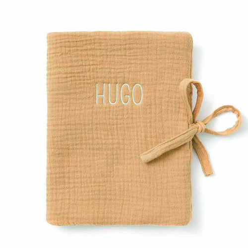 Protège carnet de santé camel brodé au prénom Hugo, fermé par un lien à nouer