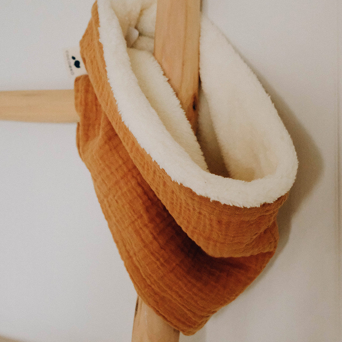 Snood camel doublé de polaire, suspendu à une patère en bois