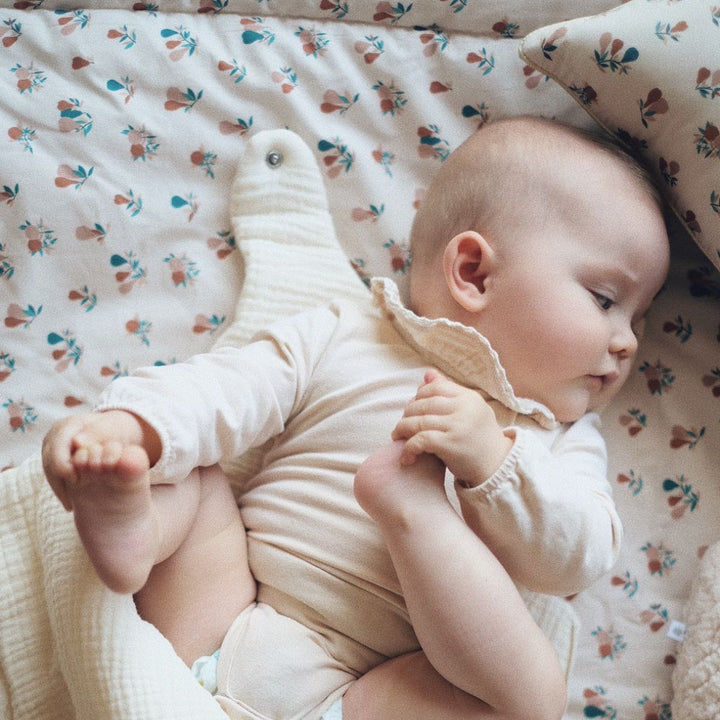 Bébé allongé sur tapis d'éveil en coton bio avec un motif poires