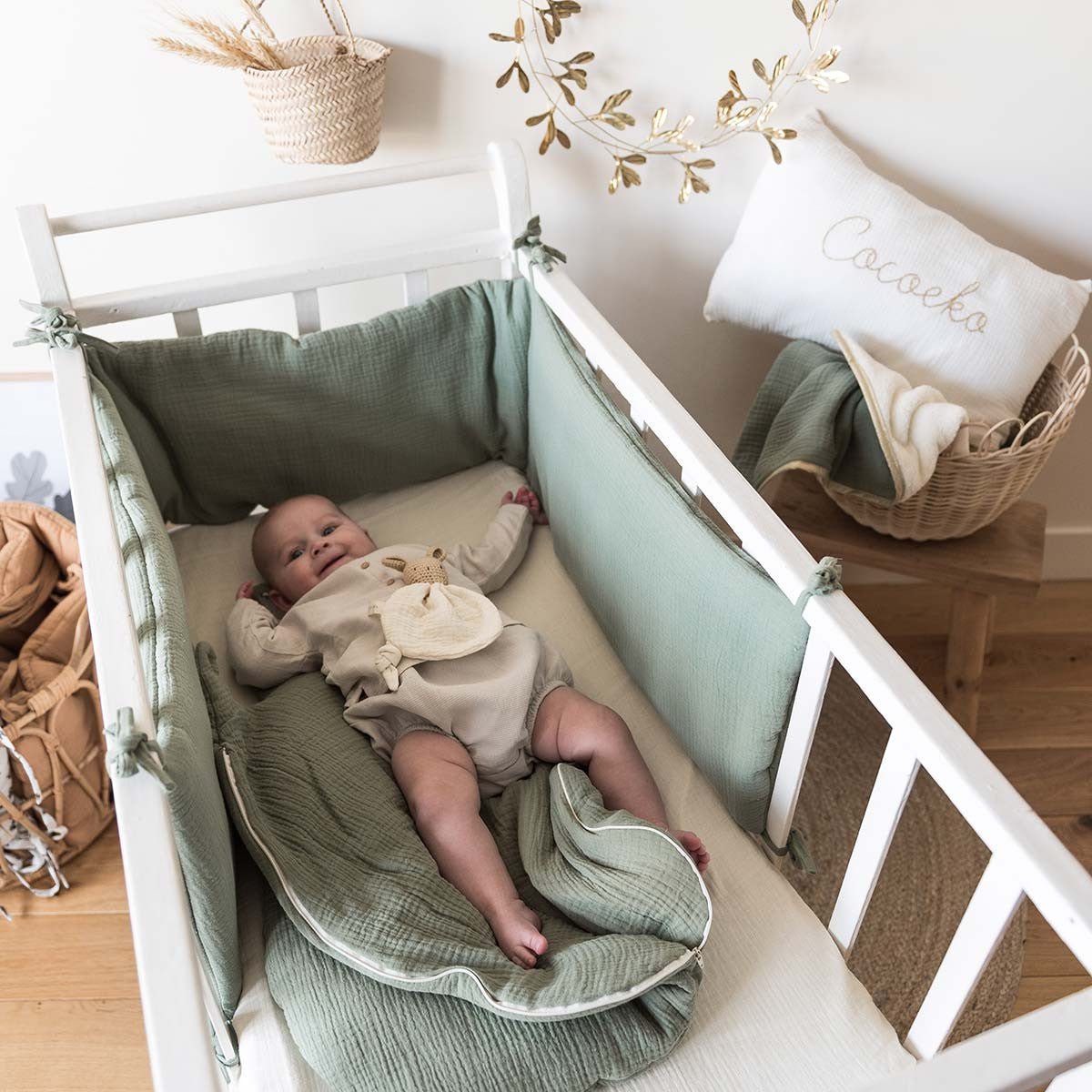 Sage green bumper pad in a crib