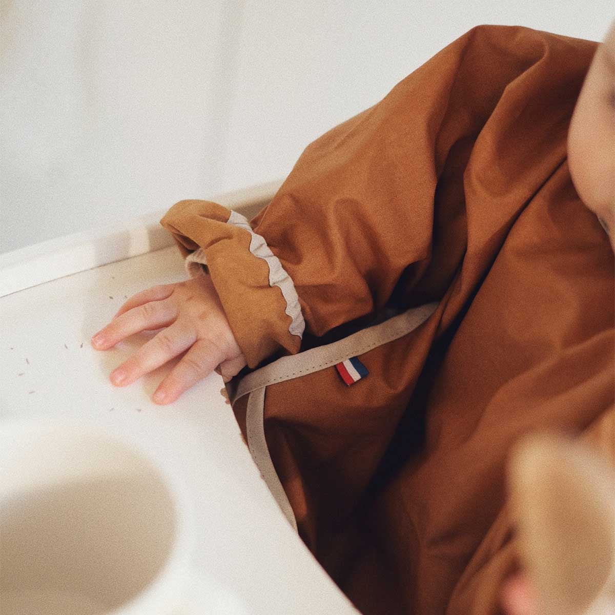 Zoom on the long-sleeved bib in plain camel